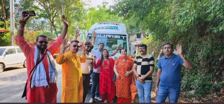 Enthusiastic pilgrims raising hands in joy by their Shree Tungnath tour vehicle