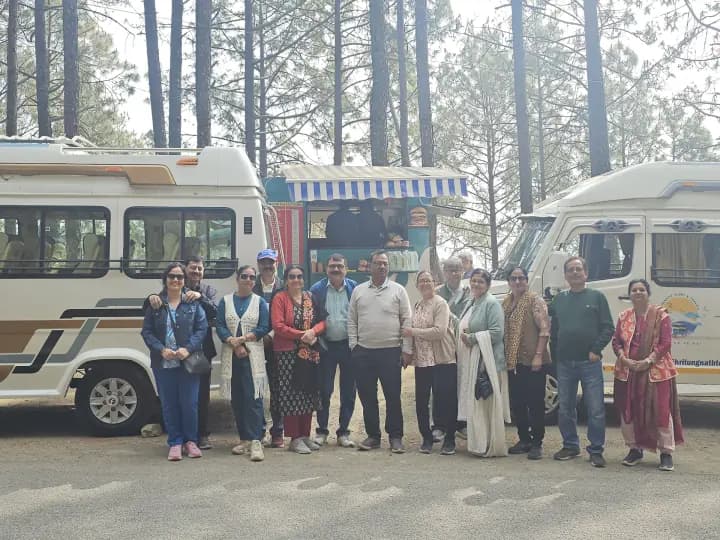 Pilgrim group assembled before luxury vehicles amidst towering Himalayan cedars
