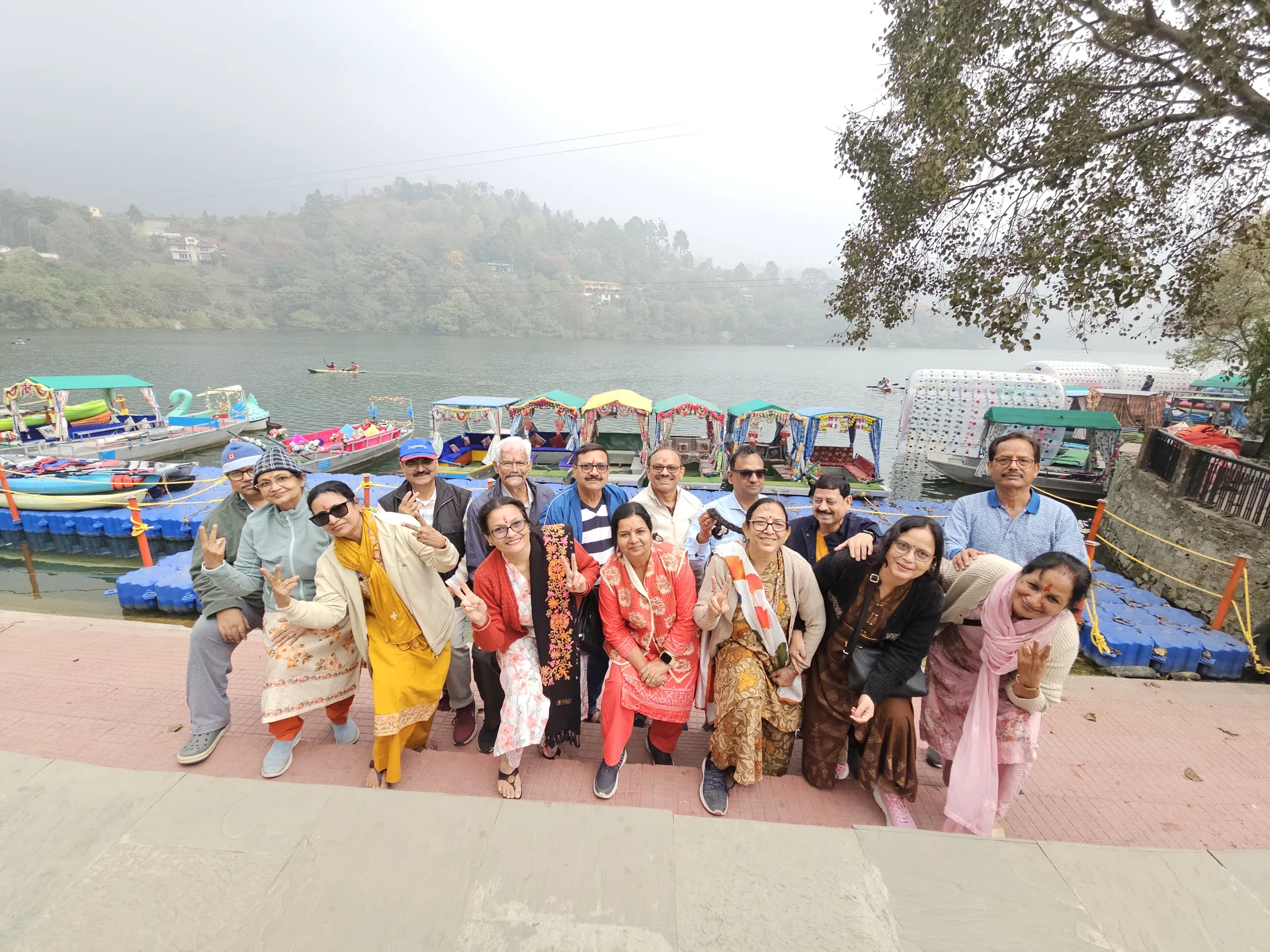 Joyful traveler group smiling at Bhimtal lakeside with paddle boats in background