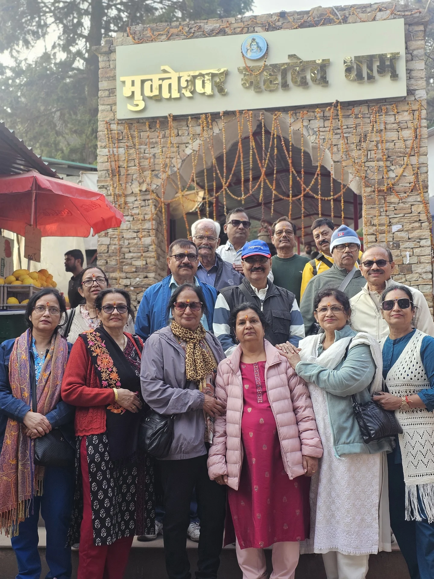 Pilgrims posing beneath the sacred archway of Mukteshwar Mahadev Dham in Uttarakhand